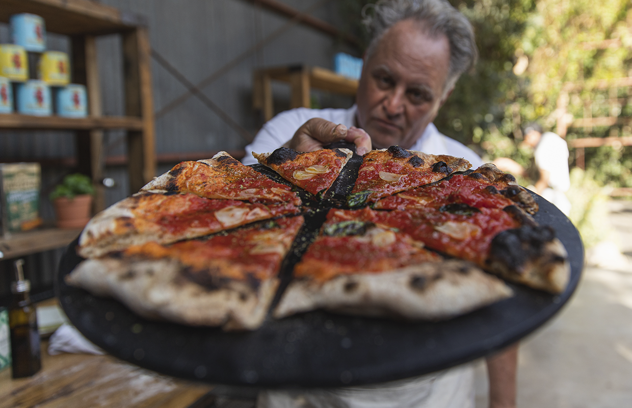Chris Bianco holding a pizza on a server